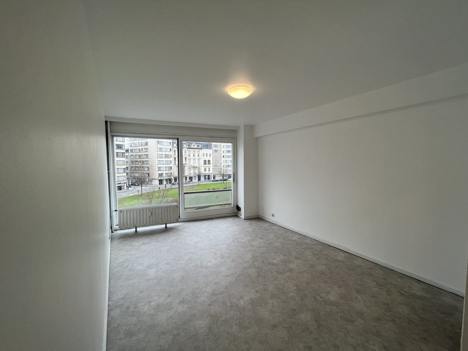 Lichte leefruimte met grote raampartij van het appartement te huur aan de Belgiëlei 66 in Antwerpen